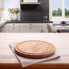 Fototapeta na wymiar Empty wooden table with pizza board and tablecloth near the window in kitchen. White Napkin close up top view mock up. Kitchen rustic background.