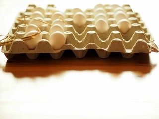 Fresh white farmers chicken eggs in a box on a table .