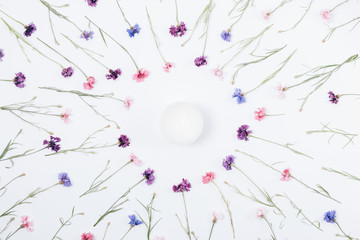 Cosmetic cream among wreath of purple, blue and pink daisies