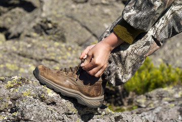 hands tying shoelaces on a worn hiking boot closeup
