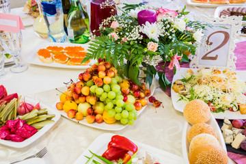 Served table at the Banquet. Fruits, snacks, delicacies and flowers in the restaurant. Solemn event or wedding.
