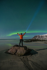 Norway - Lofoten island -  Tourist with light looking aurora