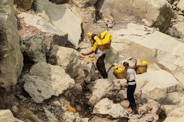 Sulfur hard workers in Indonesia on Ijen volcano climbing up with load