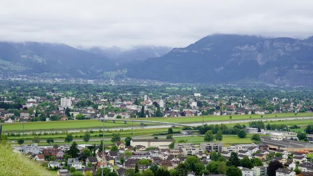 european town in the swiss alps, drone shot timelapse weather rolling in over the mountains of switzerland austria and germany with cars and trains flowing over the border