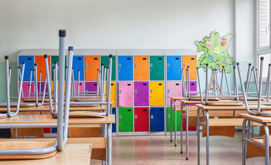 Fototapeta Empty Classroom with colorful lockers and raised chairs on the tables obraz