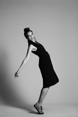 girl in a black suit with a hat, hair posing in the Studio on a gray background. black and white...