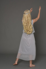 full length portrait of blonde girl wearing dress and crown. standing pose with back to the camera....