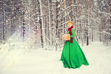 fiery red-haired woman in a ball green dress with a red leather belt in the costume of dwarf assistant Santa Claus in the winter forest with huge candy, a chest of gifts, the concept of the new year