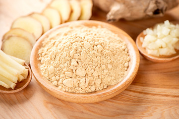 Ginger root, ginger slice and ginger powder on wooden background table, space for text.