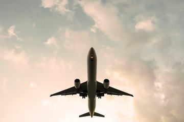 Silhouette of flying passenger plane. airplane landing during a sunset sky background. Jet civil aircraft with two engines. Orange clouds.