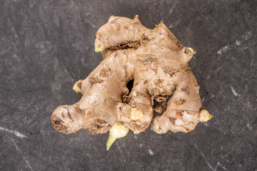 Whole ginger roots on dark old stone background table, space for text.