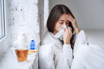 Cold and flu. Sick woman caught cold, feeling illness and sneezing in paper wipe. Closeup of...