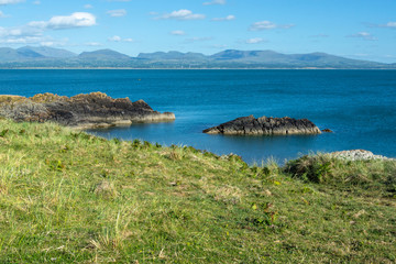 Menai Strait and Snowdonia mountains seen from rocky coast of Anglesey Island on summer evening - 1
