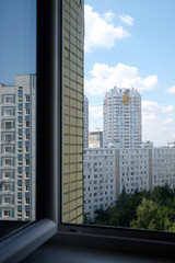 View from opened window on cityscape with dense urban development and construction  apartment buildings in the green area of the city
