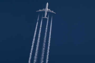 passenger plane fly with a contrail flying on the dark blue sky background