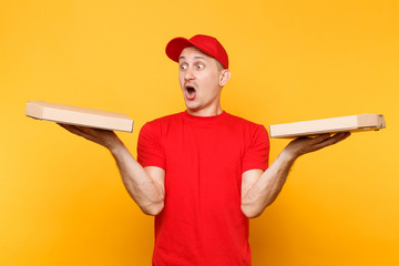 Delivery man in red cap, t-shirt giving food order pizza boxes isolated on yellow background. Male...