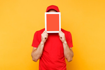 Delivery man isolated on yellow orange background. Professional male employee courier in red cap, t-shirt holding tablet computer with blank empty screen. Service concept. Copy space. Mockup template.