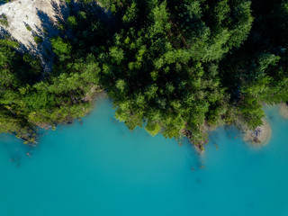 Aerial drone photo of green tree crones growing in tourquoise water of abandoned kaolin quarry, top...