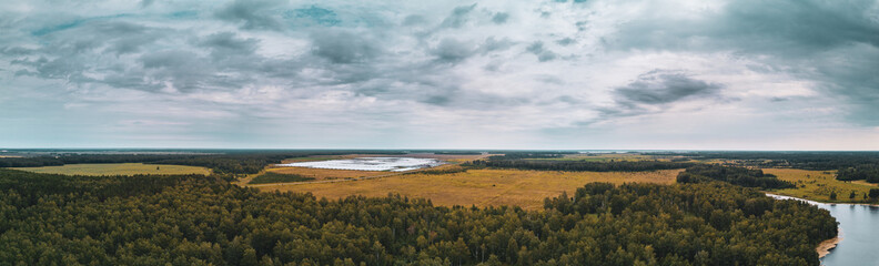 Fototapeta na wymiar Aerial drone panoramic view of fields landscape, deep mixed forest, planting in greenhouses on the background, long panoramic photo in autumn evening in harvest season, South Ural, Russia