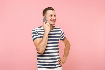 Portrait of fun emotional young man talking on mobile phone, conducting pleasant conversation isolated on trending pastel pink background. People sincere emotions lifestyle concept. Advertising area.