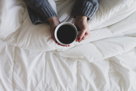 Woman Holding Black Coffee In Bed