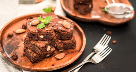luxurious dessert, chocolate brownie cake in a wooden plate on a black background, space for text