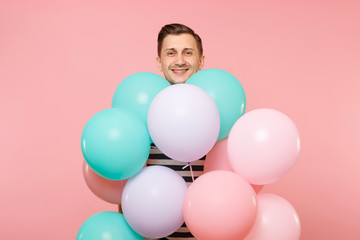 Fototapeta na wymiar Portrait of fascinating young happy man wearing striped t-shirt holding colorful air balloons isolated on bright trending pink background. People sincere emotions lifestyle concept. Advertising area.