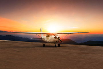 old propeller plane taxi on airport runway against beautiful sun set sky
