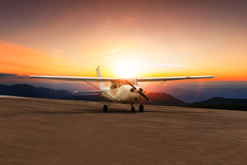 Fototapeta na wymiar old propeller plane taxi on airport runway against beautiful sun set sky