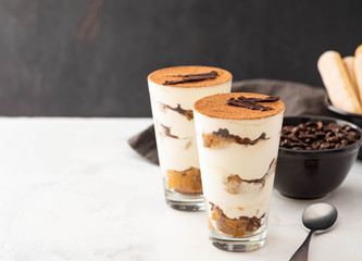 Homemade tiramisu, traditional Italian dessert in glass on white table. Copy space.