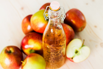 Bottle of fresh apple cider and half apple near autumn apples
