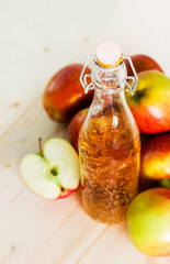 Bottle of fresh apple cider and half apple near autumn apples