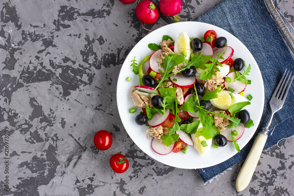 Wall mural nicoise salad with tuna, egg, cherry tomatoes and black olives on dark grey background. french cuisi