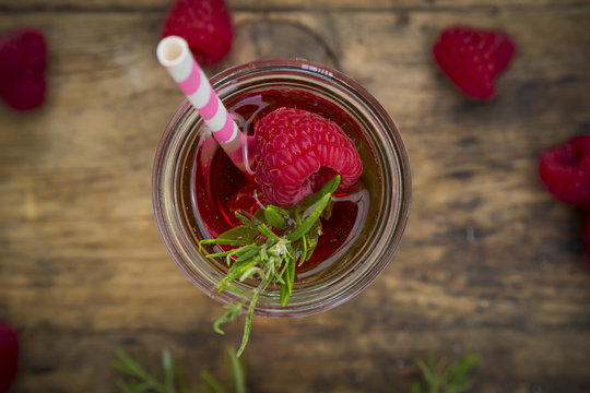 Glass bottle of homemade raspberry lemonade flavored with rosemary