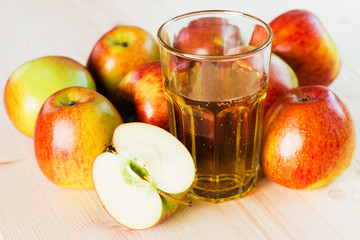 Glass of fresh apple cider and half apple near autumn apples.