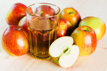 Glass of fresh apple cider and half apple near autumn apples.