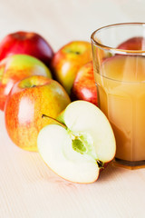 Glass of fresh apple juice and half apple near autumn apples.