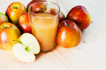 Glass of fresh apple cider and half apple near autumn apples.