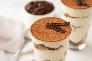 Tiramisu in a glass with coffee beans on white background. Copy space.