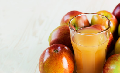 Glass of fresh apple cider near autumn apples