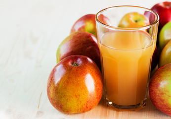 Glass of fresh apple juice near autumn apples