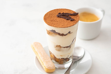 Tiramisu in a glass with coffee beans on white background. Copy space.