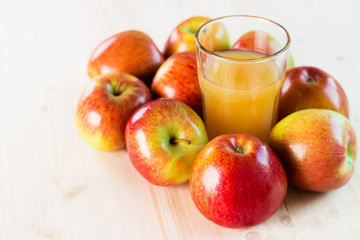 Glass of fresh apple juice near autumn apples