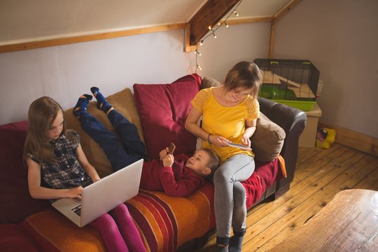 Family on sofa using multimedia devices