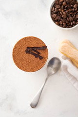 Tiramisu in a glass with coffee beans on white background. Copy space. Top view.