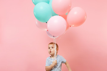 Playful little cute child baby boy holding bunch of colorful air balloons, celebrating birthday...
