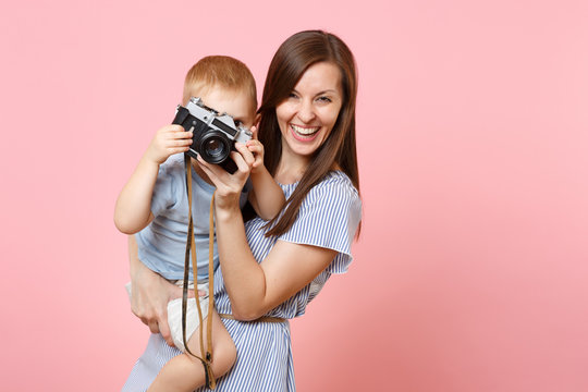 Portrait of happy family. Mother keep in arms, have fun, hug son baby boy, take picture on retro vintage photo camera on pink background. Sincere emotions, Mother's Day, parenthood, childhood concept.