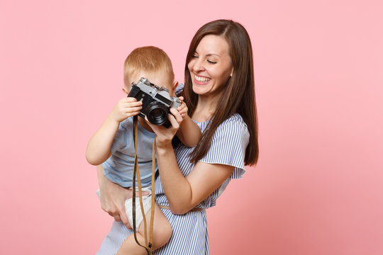 Portrait of happy family. Mother keep in arms, have fun, hug son baby boy, take picture on retro vintage photo camera on pink background. Sincere emotions, Mother's Day, parenthood, childhood concept.