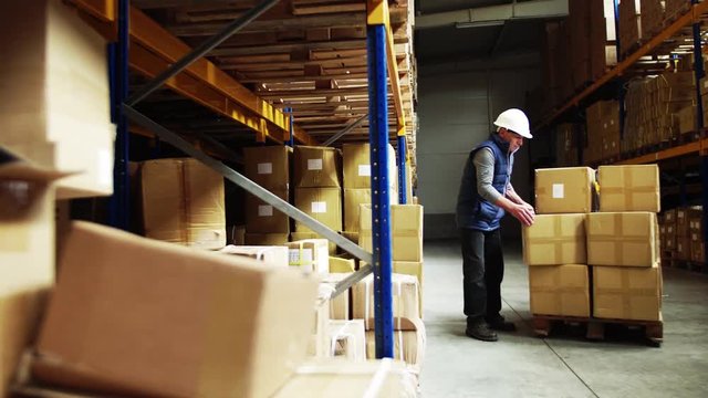 Senior male warehouse worker unloading boxes from a pallet truck.