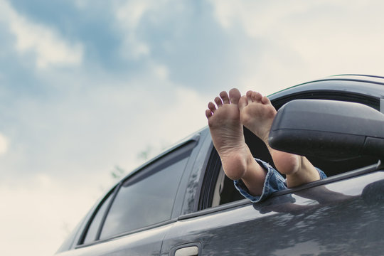 Summer road trip car vacation concept. Woman legs out the windows in car. Conceptual freedom, travel and holidays image.
